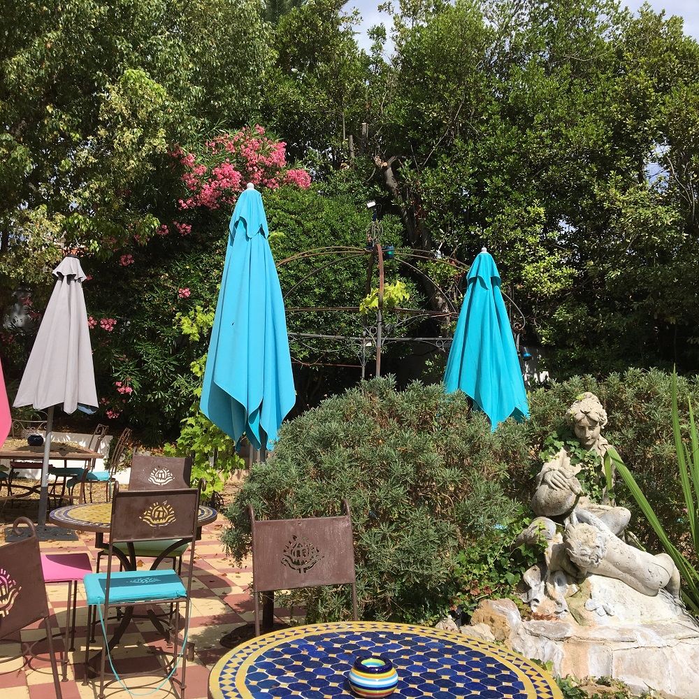 Le Pre Catalan hotel garden with parasols, statues, little fountain and trees
