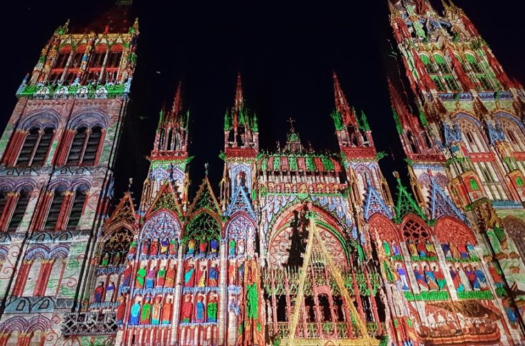 Lookingup at facade of Rouen Cathedral with lights flickering over the front