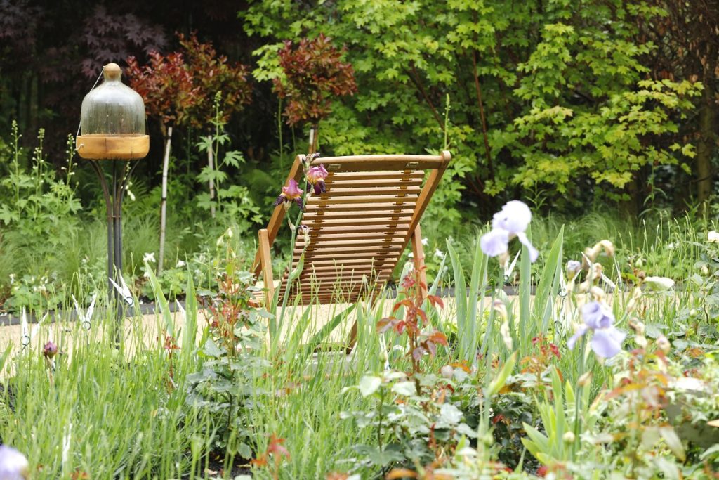 Chaumont garden festival garden with wooden deck chair among beds of wild flowers