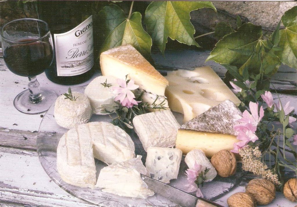 Bottle of Gigondas wine in background and many different cheeses on plateau