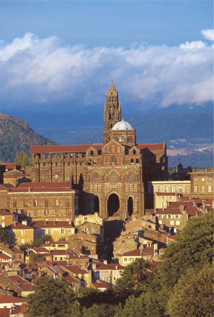 View from afar of Le Puy en Velay cathedral high abaove the town with red rooves, huge tower