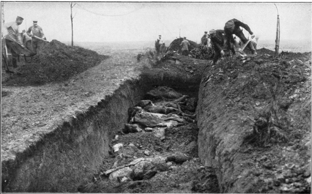 Old black and white photograph of a mass grave at Fromelles with soldiers burying bodies