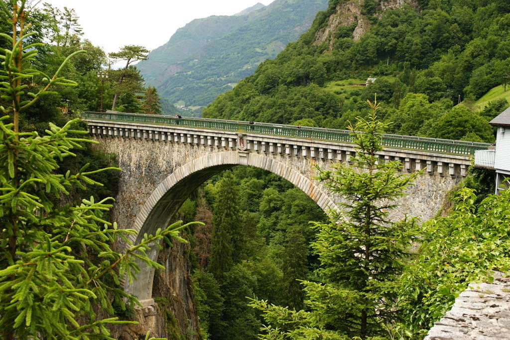 High stone bridge over the river in Luz Saint-Sauveur with mountains in background