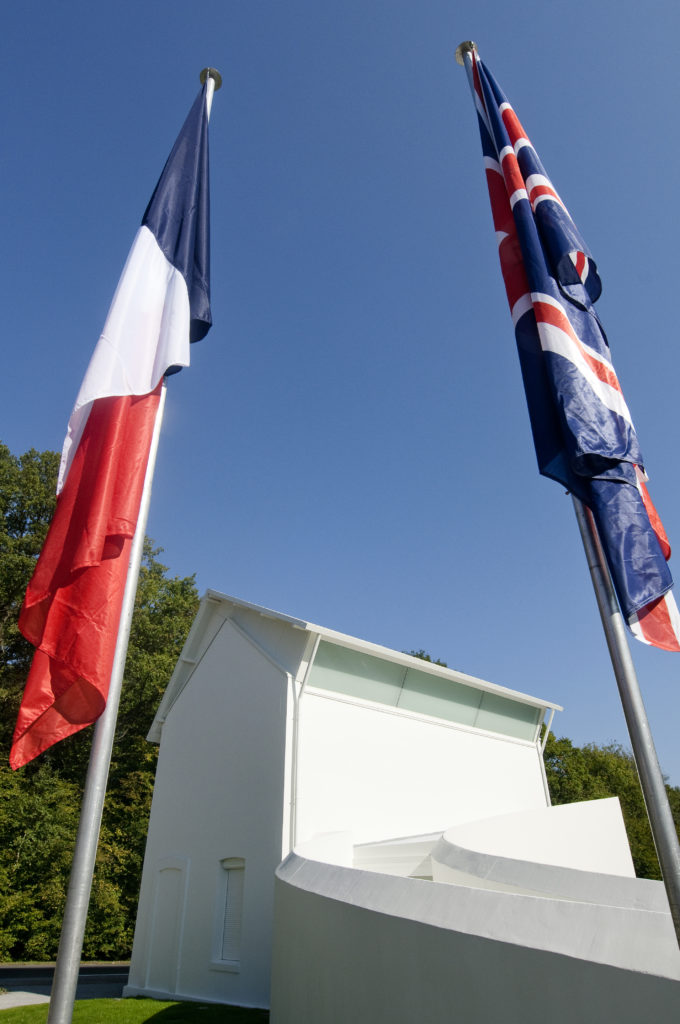 British and French flags on flagpoles outside the white Wilfred Owen memorial