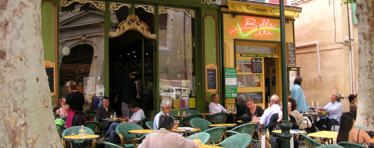 Restaurant in Isle-sur-la-Sorgue with terrace and tables, chairs and customers under awning on terrace
