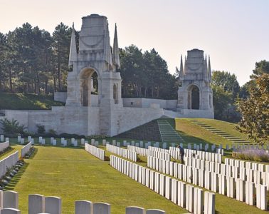 Etaples Military Cemetery with two memorial gates in background and ranks of graves in foreground in unusual perspective