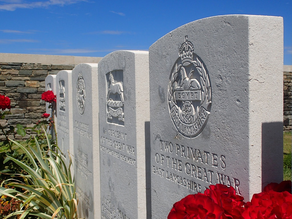 Four close ups of headstones in Serre No 3 military cemetery with red flowers in front hem