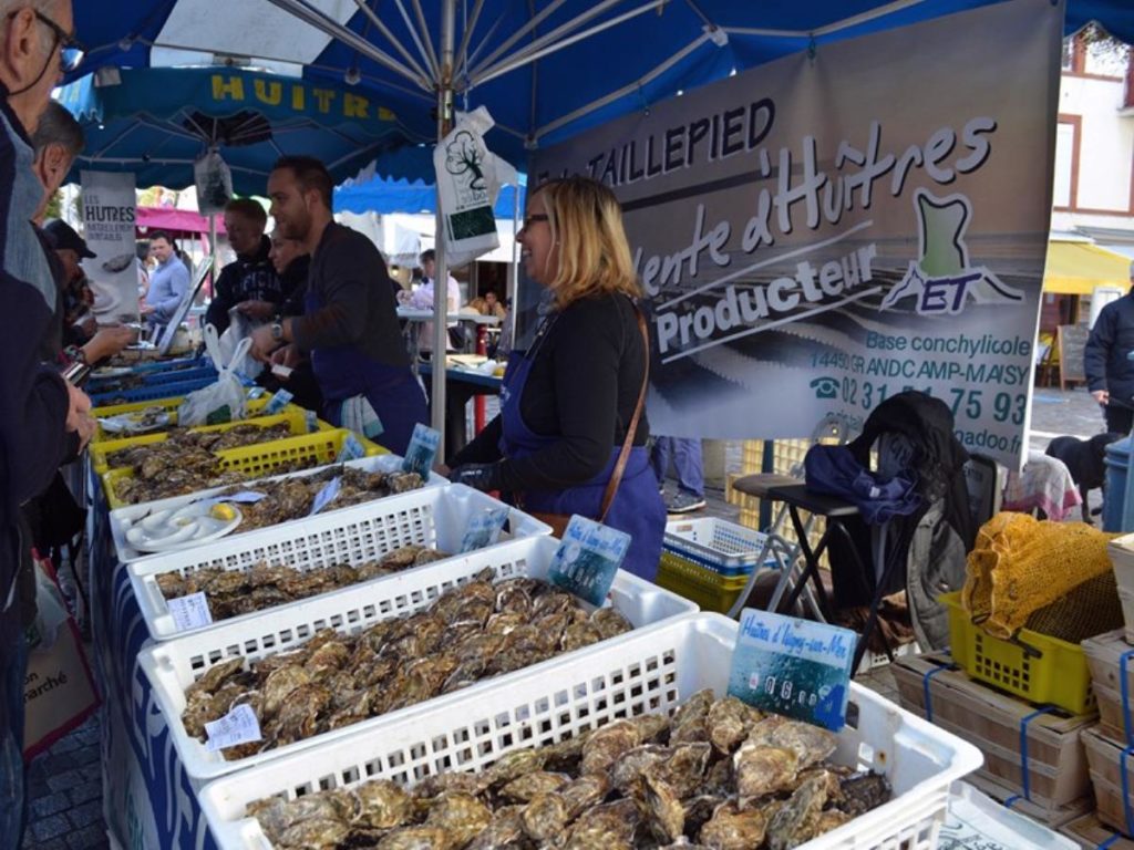 Stall selling shellfish with shellfish in plastic boxes and two people serving