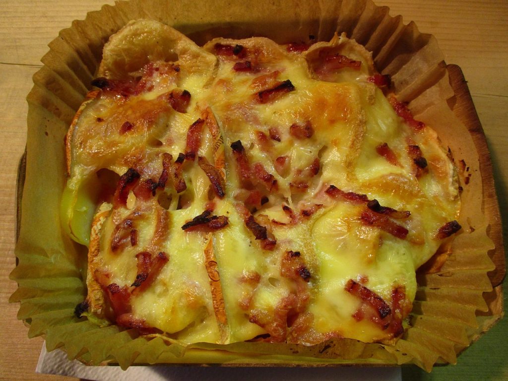 Tartiflette baked cheese, potato, onion in a cardboard take away case