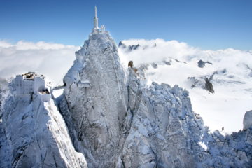 Aiguille in the Alps seen from afar; hugely tall piak with radio mast on top in snowy Alps