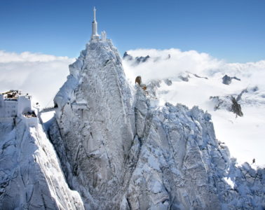 Aiguille in the Alps seen from afar; hugely tall piak with radio mast on top in snowy Alps