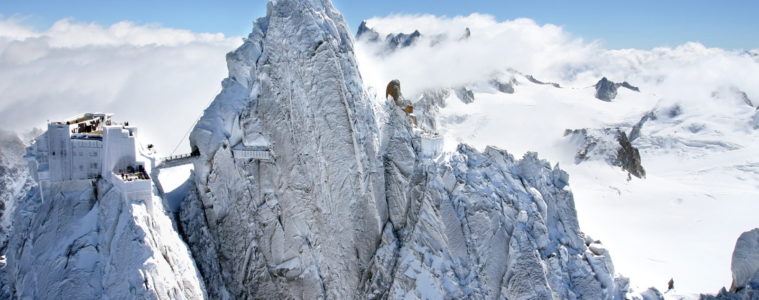 Aiguille in the Alps seen from afar; hugely tall piak with radio mast on top in snowy Alps