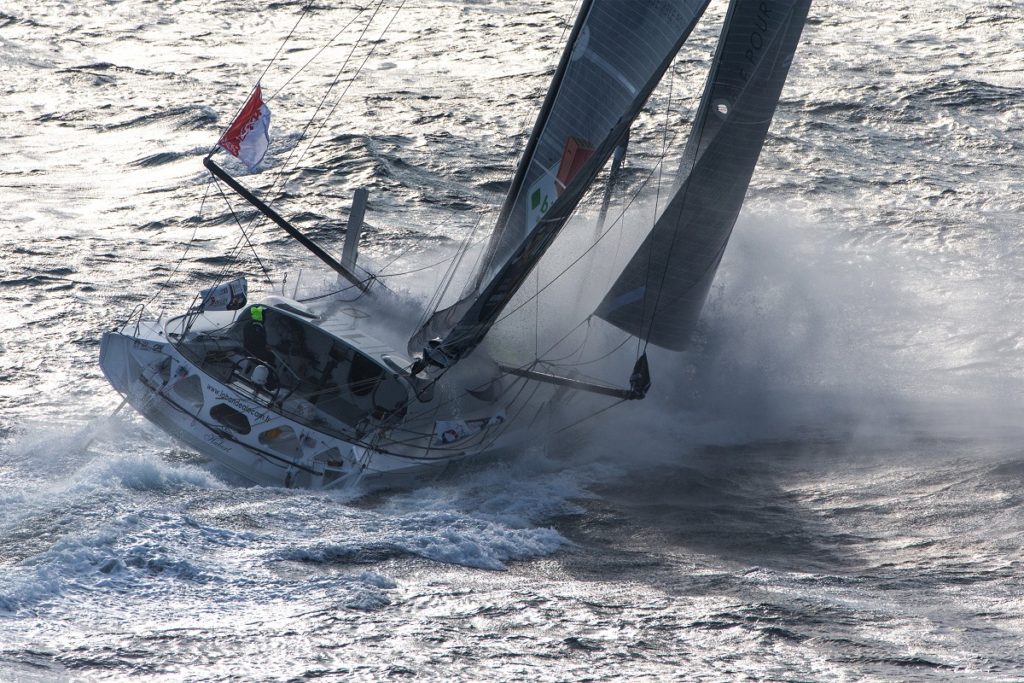 Vendee Globe race in action with yacht leaning over in empty sea