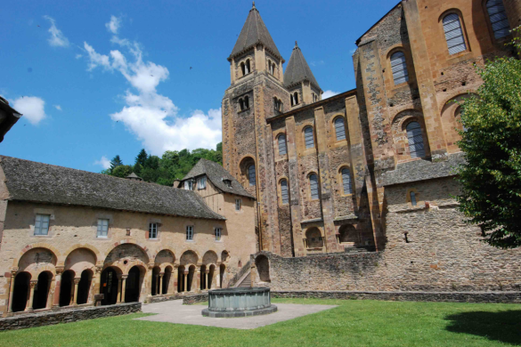 Cloisters of Abbey of Sainte Foy in conques looking across green lawn at arcaded cloisters on left adjoined to the side of the Abbey