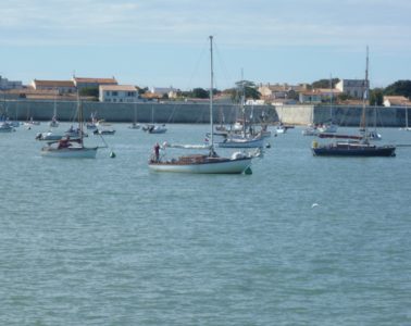 Ile d'Aix harbour looking fromthe sea to yachts bobbing upand down, with defensive walls and houses behind in the harbour