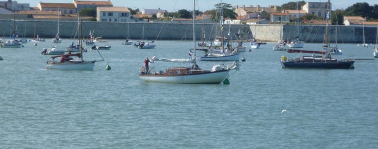 Ile d'Aix harbour looking fromthe sea to yachts bobbing upand down, with defensive walls and houses behind in the harbour