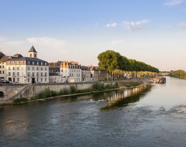 Loire river at Orleans with large river in central part, and buildings on left bank, white stone with tower in distance