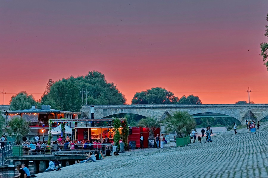La Sardine cafe on the banks of the River Loire Orleans at dusk with bridge in background, trees and tables and chairs in outdoors