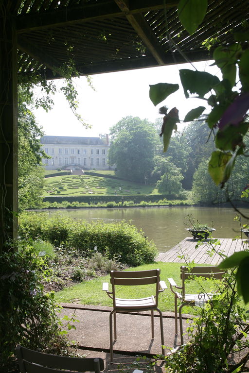 Parc Floral in Orleans looking from shady river bank with chairs over water and to chateau in distance on a hill