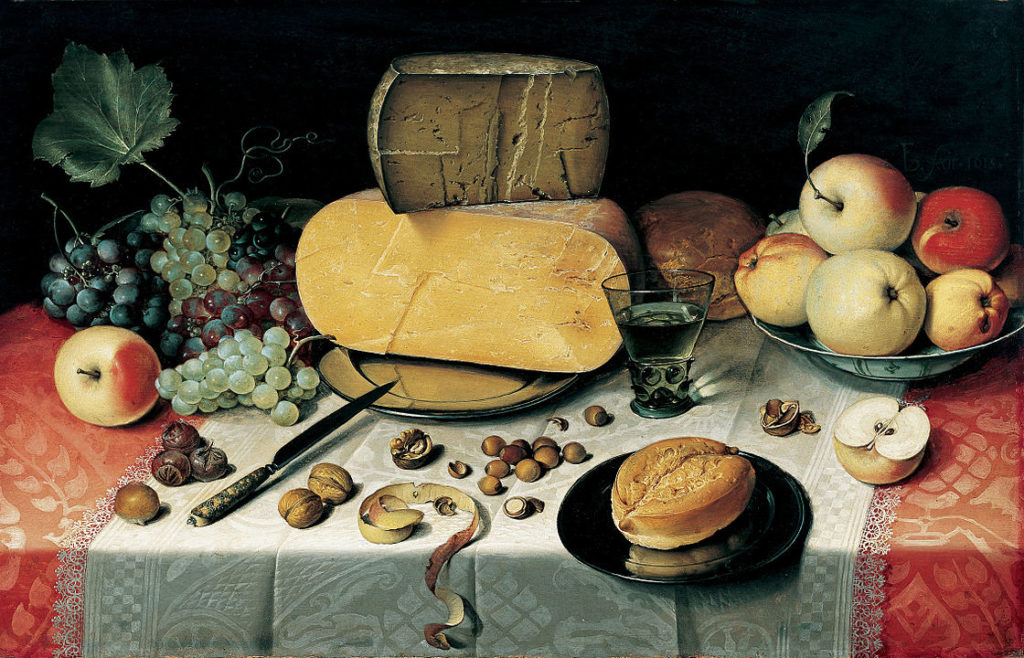 Still life of Medieval table with cheesses in background, board, bread, knife and nuts scattered on table