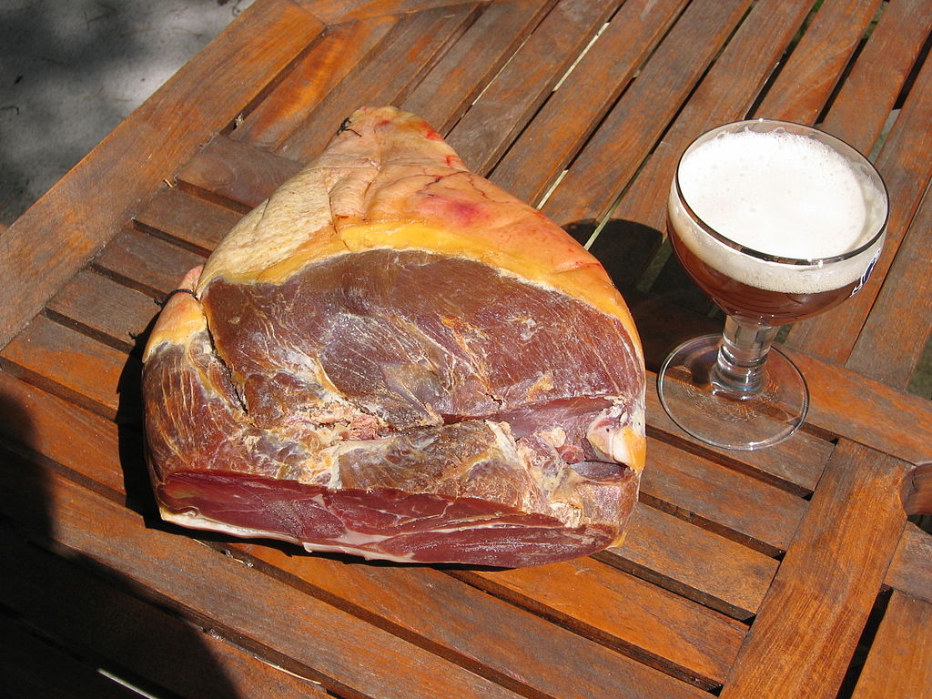 Cured ham from the Ardennes France, with outdoor rtable with big leg of cured ham and glass of beer