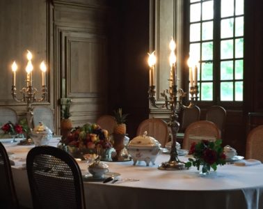 Dining table laid with candlesticks, elaborate china and glass and linen at Chateau de Cirey