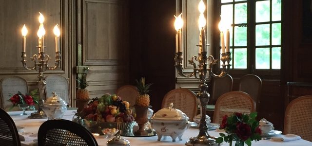 Dining table laid with candlesticks, elaborate china and glass and linen at Chateau de Cirey
