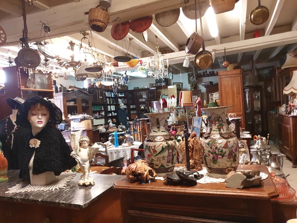 La Brocante de Brigitte in Le Perche, Normandy showing complete jumble of odd objects from a half bust of a woman in plaster with hat and cloak on to glasses, jugs, objects hanging from the wooden rafters