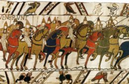 Bayeux Tapestry with many English soldiers on horseback in warm colours with beasts in bottom panel and birds and two men wrestling in top