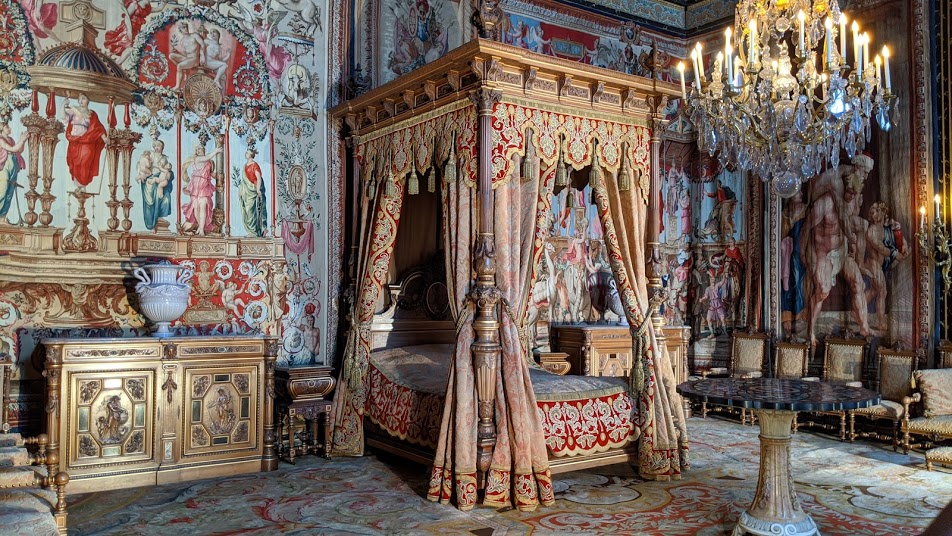 Queen Anne of Austria's Bedroom in the Chateau of Fontainebleau. VEry ornate four poster bed in centre with ornate tapestry covered walls