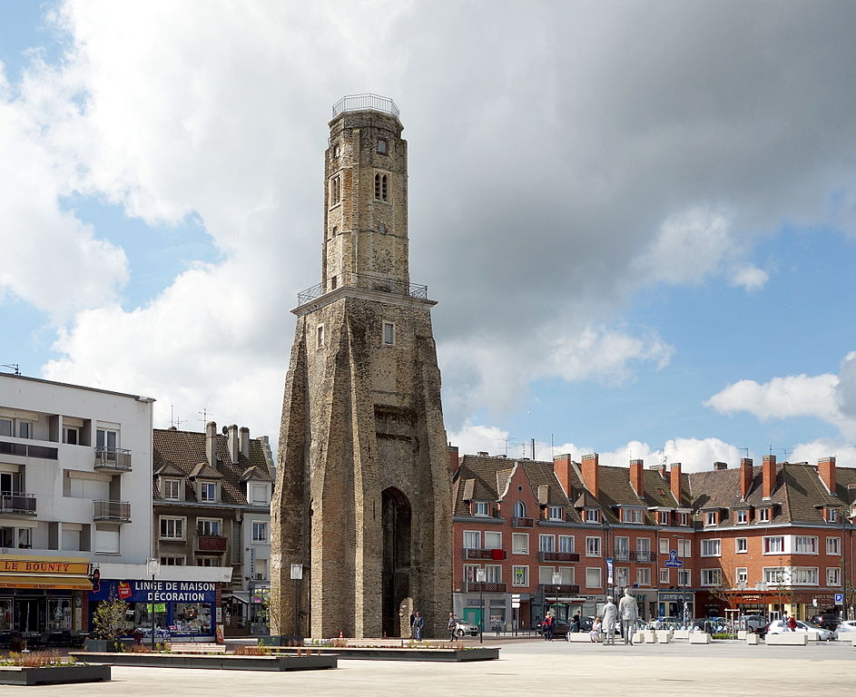 Tour du Guet in Calais. Stone tower in middle of square with shops behind and figures in square. Originally medieval