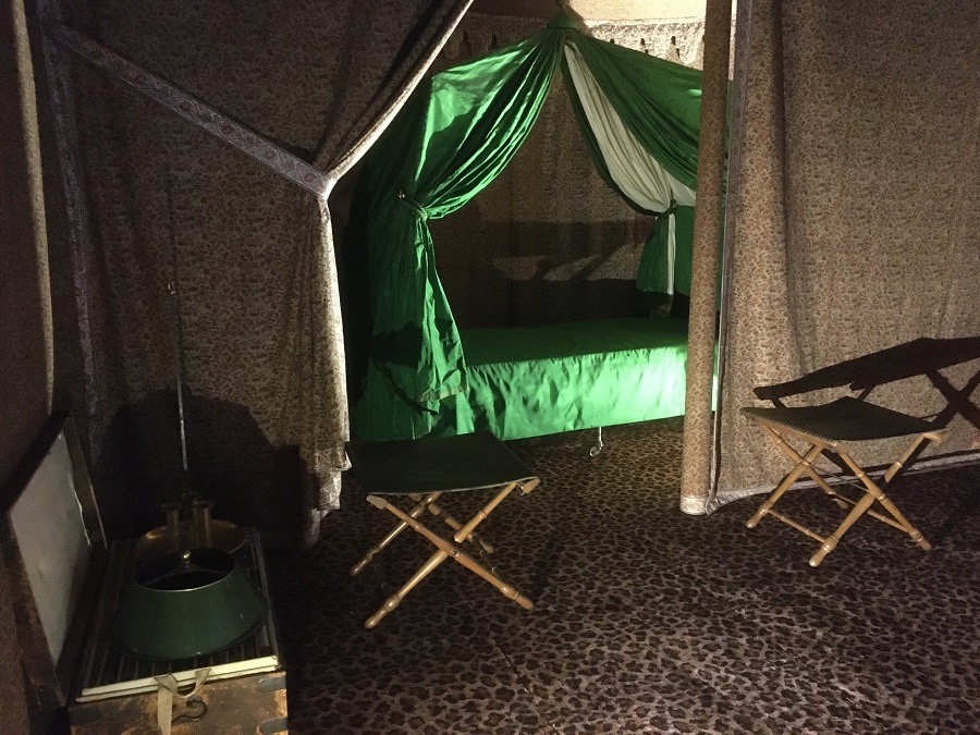Napoleon's tent at Chateau of Fontainebleau in dark room with green canopied tent and small stool in front