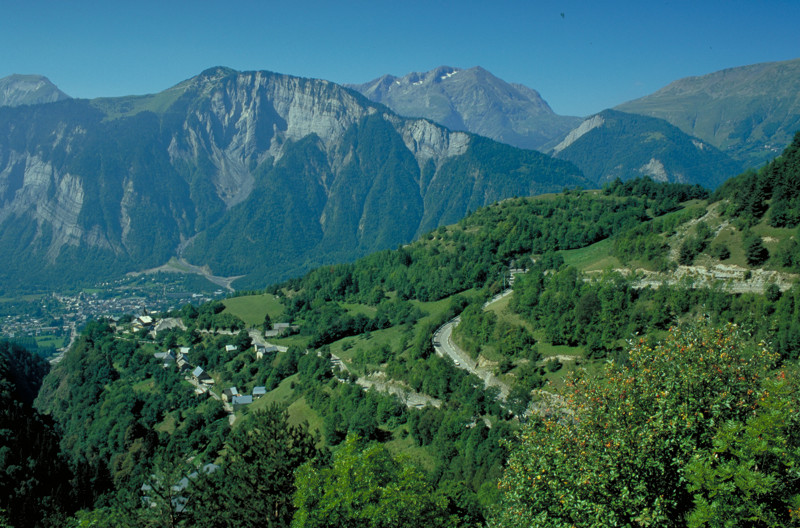 Long shot ot the hairpin winding road up through the valley to Alpe d'Huez with mountain in background