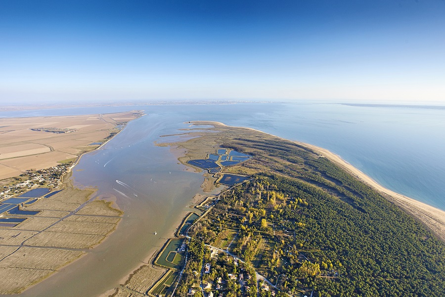 Aerial view of Aiguillon Bay in the Vendee showing huge sand bar with water in between and town and green woods on right
