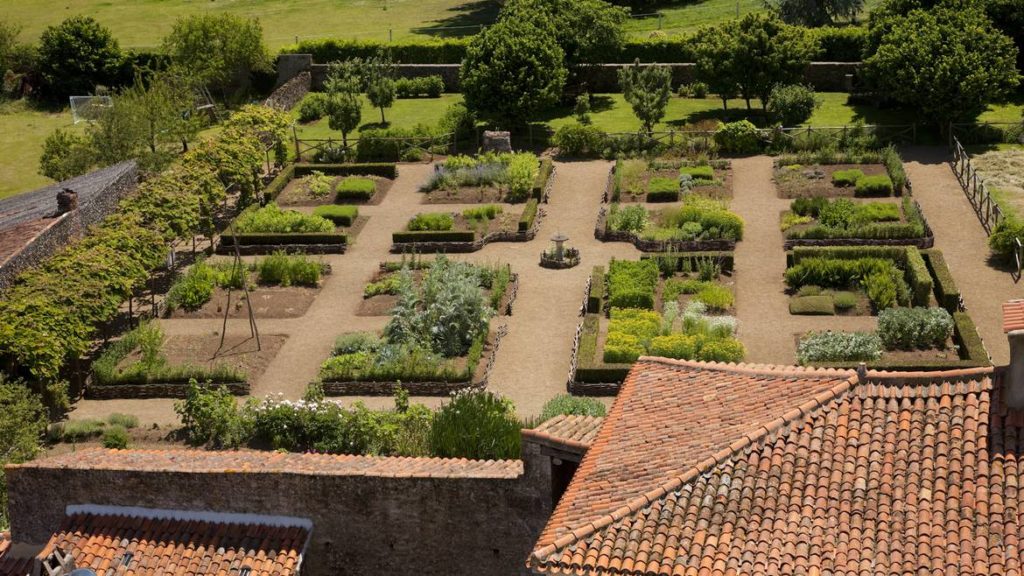 Looking from above with tiled roof then onto medieval garden at Bazoges en Preds i nVendee with beds laid out symetrically