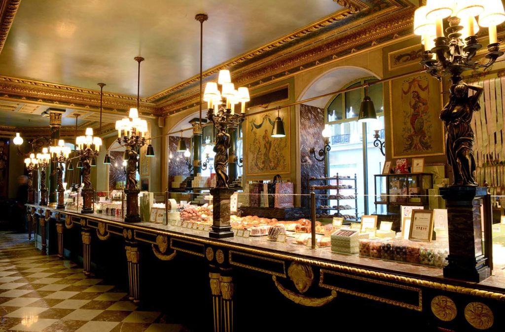 Inside Ladurée in Paris whoing Art Deco decoration with huge old lamps, windows and counter stocked with food items