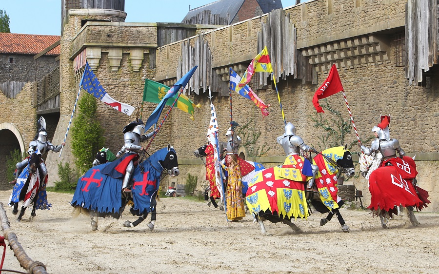 Puy du Fou knights onhorseback with armous and hoses covered in long flowing flags charging forward