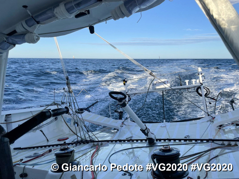 Giancarlo Pedote in Vendee Globe 2020 looking from back to boat to front with sea swirling around and mast at top of picture