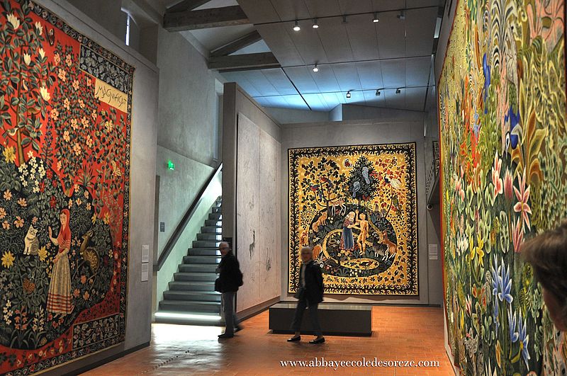 Large main room of Dom Robert Museum showing woman sitting on bench looking at huge tapestries hung on walls