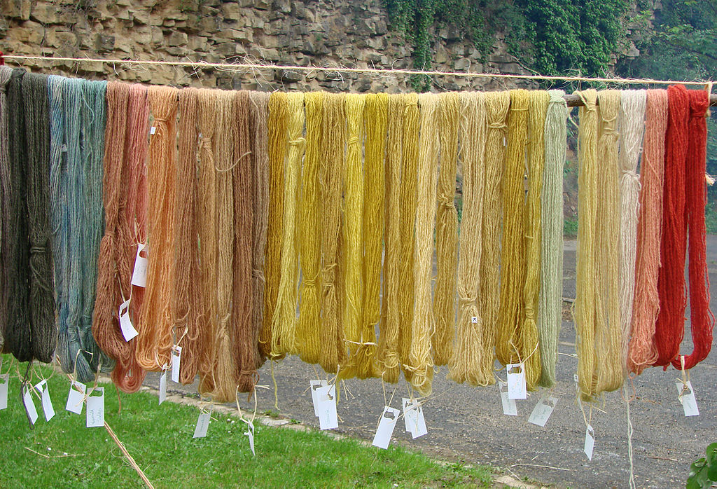 Skeins of wool hanging up to dry at the Sedan medieval fair in pale colours from green to ochre
