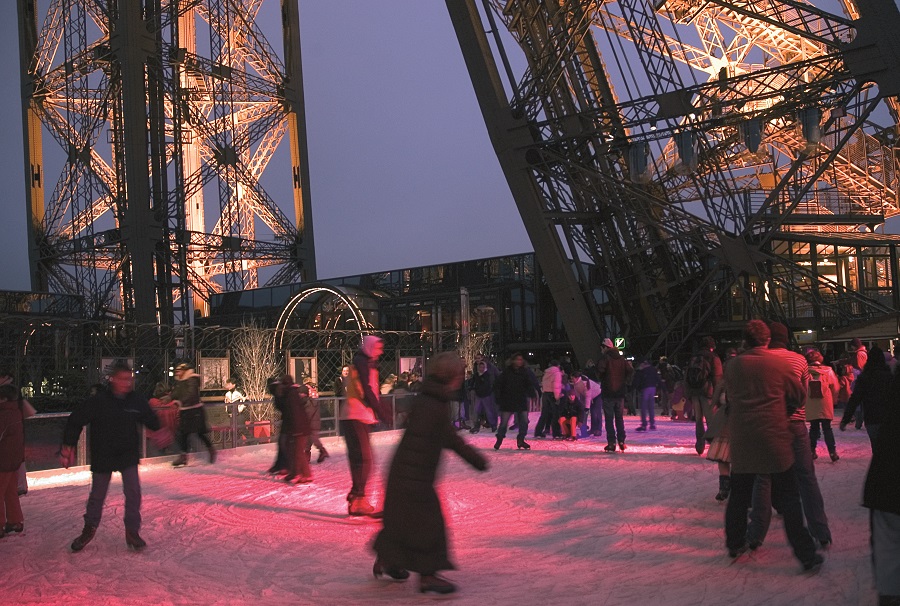 Night skating under the Eiffel Tower with figures on skates and lit by red glow