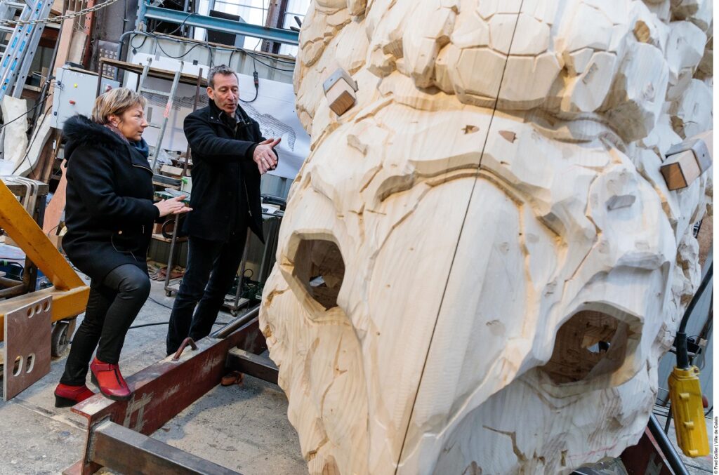 Natacha Bouchart mayor of Calais and Francois Delaroziere, creator, looking at the wooden head of the dragon of Calais