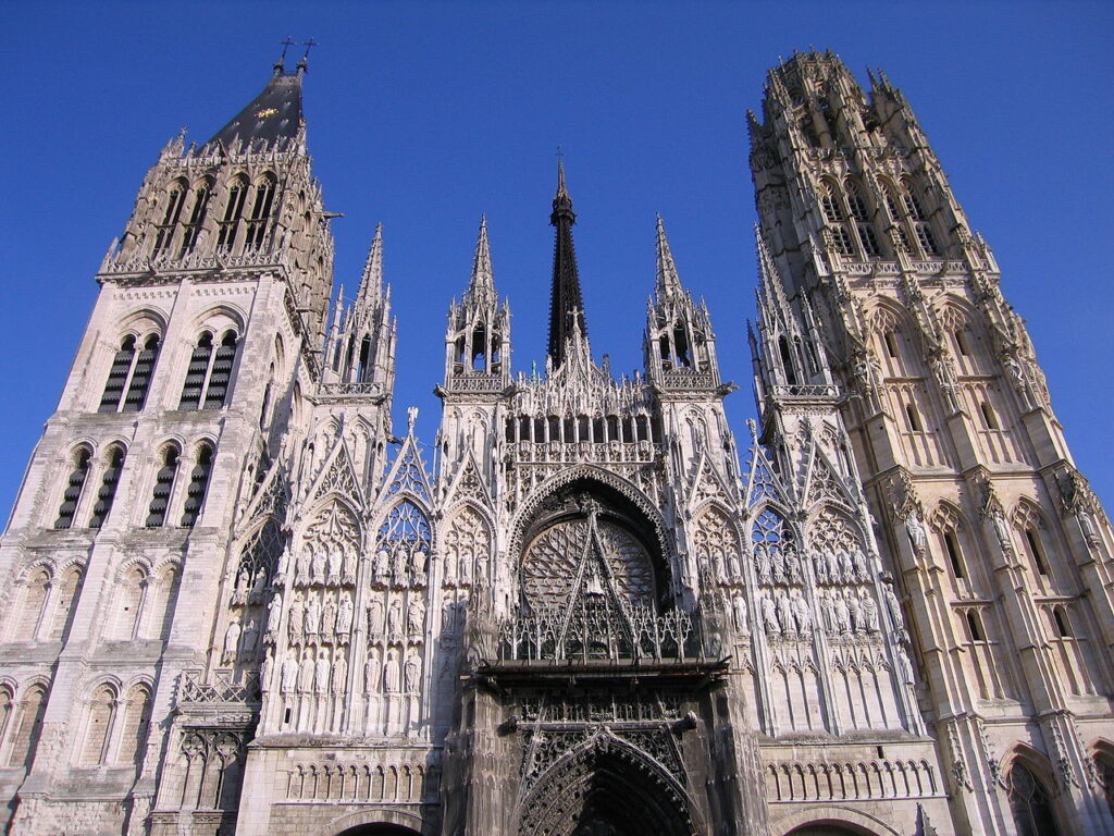 Looking up at facade of Rouen Cathedral showing towers and intricate stonework