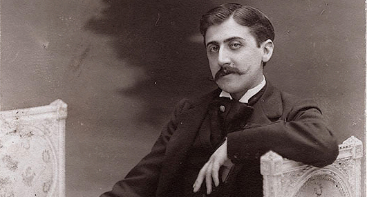 Black and white postcard of Marcel Proust c. 1895 showing author sitting nonchalantly with left arm propped up, moustache in smart suit