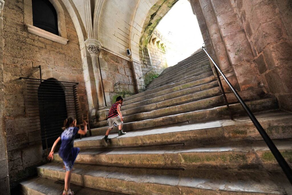 wide stone staircase going up inside Rocamadour with two children climbing steps