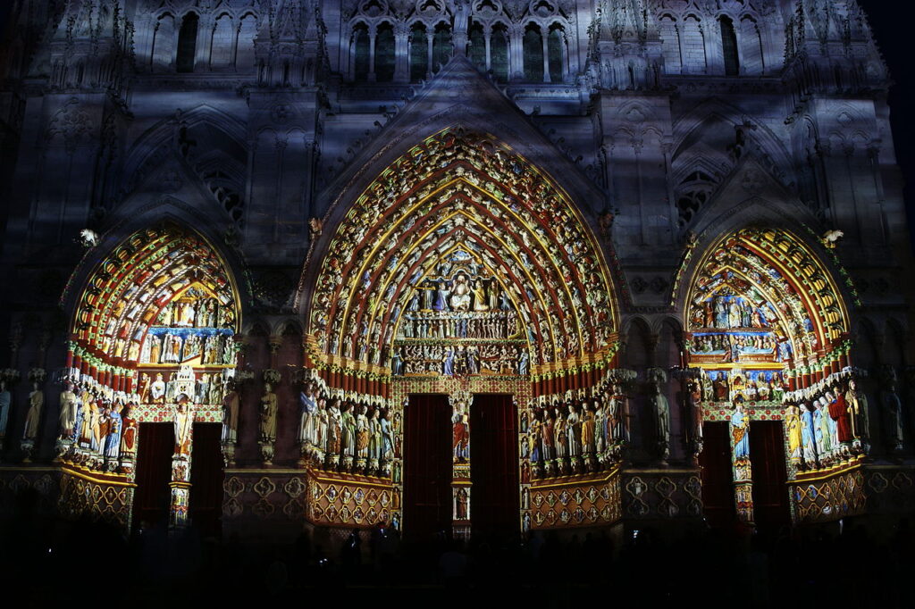 Light show very brightly coloured over the main doorway of Amiens cathedral at night