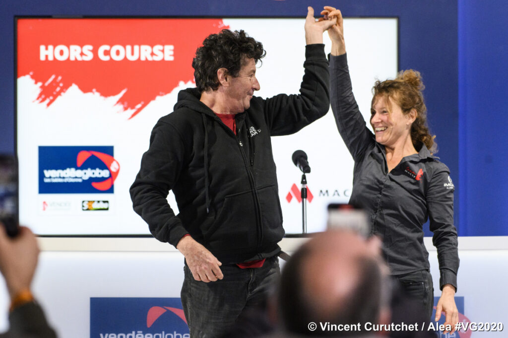 Isabelle Joschke and Jean le Cam at her press conference at the Vendee Globe race. Both holding hands high above their heads with Vendee Globe screen at back