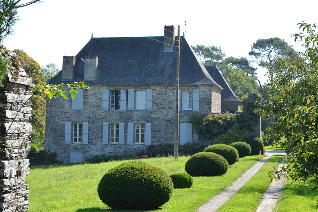 Maison de maitre in Loire Atlantique showing substantial 2-storey stone house with steep pitched slate roof, shutters onthe windows looking out onto lawn at front on a slope with symetrical cone shaped box trees along path