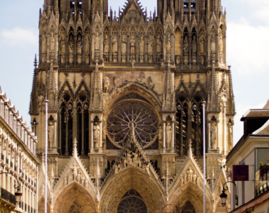 Full on view down street with classical facades to the three doorways and twin towers of Reims Cathedral