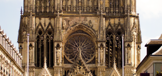 Full on view down street with classical facades to the three doorways and twin towers of Reims Cathedral